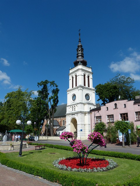 62.JPG - 62 Uniejów nie ma ratusza, ale na rynku w oczy rzuca się wolnostojąca, 25-metrowa, neobarokowa dzwonnica, która pełni też funkcję zegara. Na zdjęciu za dzwonnicą XIV-wieczna kolegiata pw. Wniebowzięcia NMP.